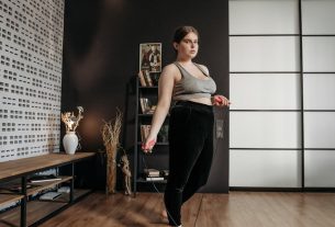 A woman performs a jump rope workout at home, focusing on fitness and health.